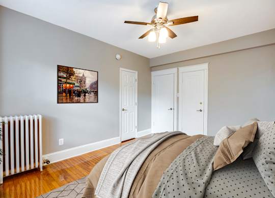 A bedroom with a bed, a ceiling fan, and a picture on the wall.