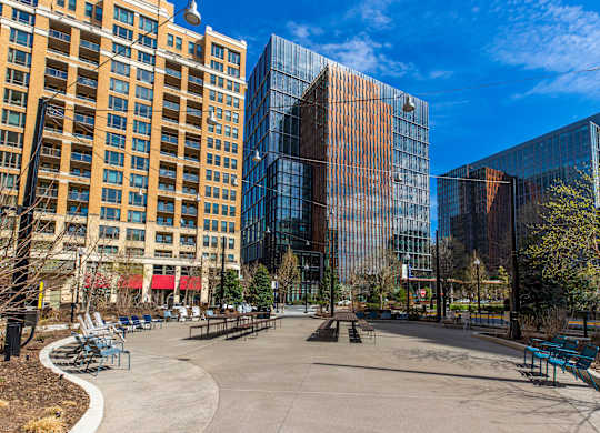 A park with benches and a walkway in front of a glass building.