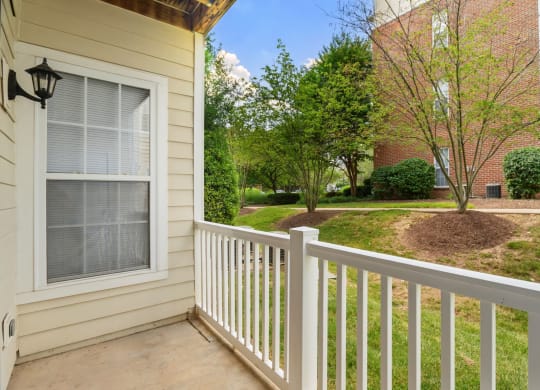 a porch with a white railing and a brick building in the background at The Residences at King Farm, Maryland, 20850