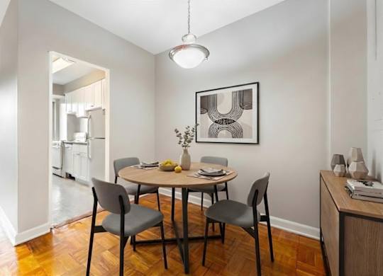 A dining room with a table set for two and a framed picture on the wall.