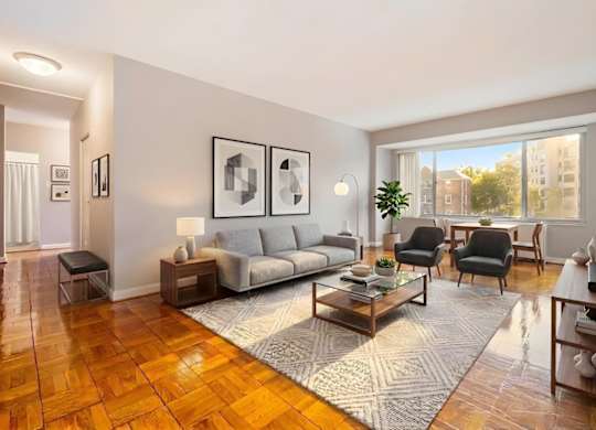 A living room with a grey sofa, a grey couch, a grey chair, a grey rug, a grey coffee table, a grey floor lamp, a grey wall, a grey door, a grey wall, a grey wall, a grey