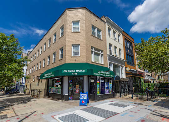A street view of a building with a green awning that reads