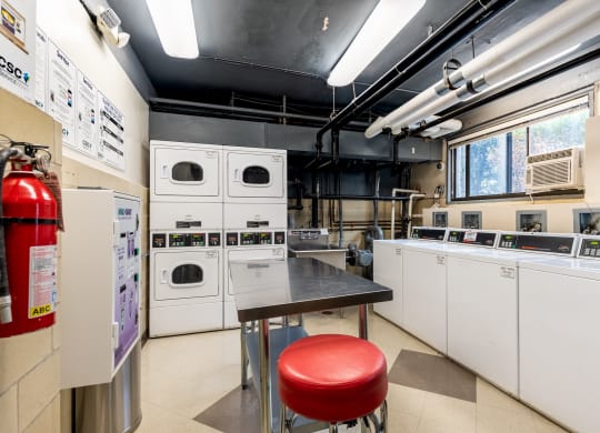a kitchen with white appliances and a table with a red stool