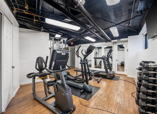 a gym with treadmills and other exercise equipment on a wooden floor