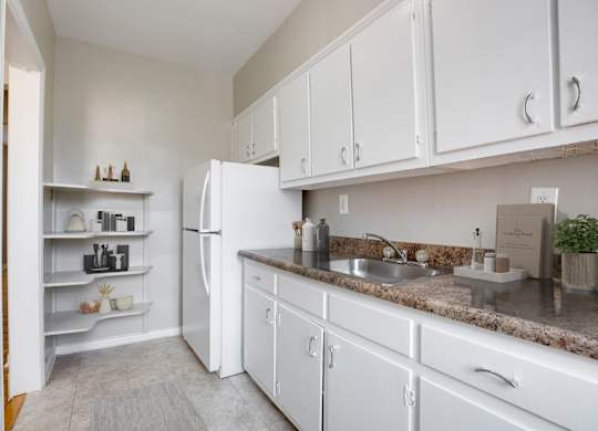 A kitchen with white cabinets and a granite countertop.
