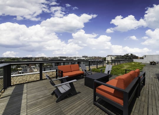 a rooftop deck with orange and black furniture and a blue sky with white clouds at The Shay, District of Columbia