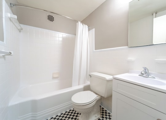 a bathroom with white fixtures and a black and white checkered floor