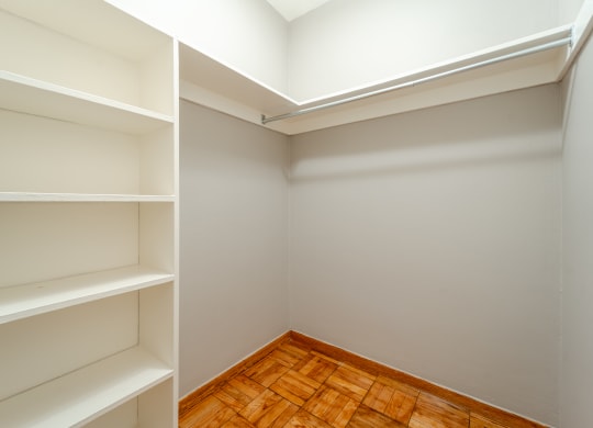 a walk in closet in a home with gray walls and a wooden floor