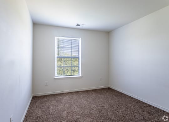 a bedroom with white walls and a window