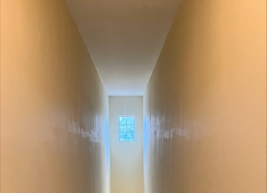 a narrow hallway with a small window at the end of the hallway