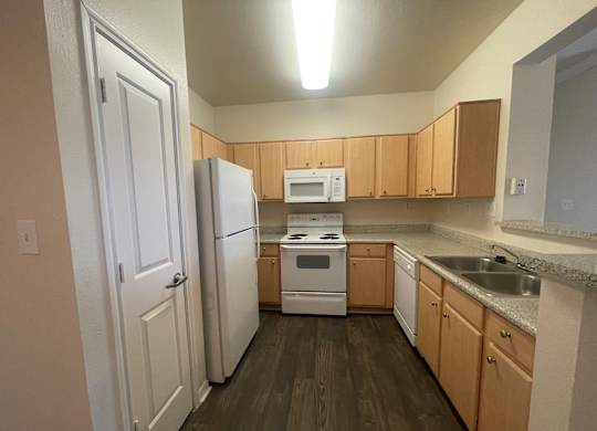A kitchen with a white refrigerator, white oven, and wooden cabinets.