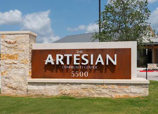 The sign for The Artesian Community Center is brown and white.
