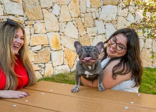 two women sitting at a table with a dog