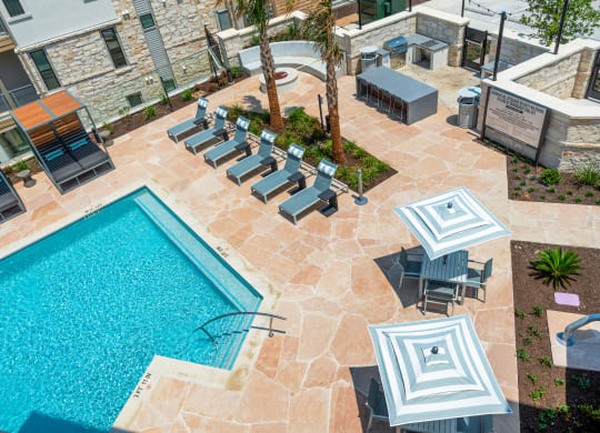 an aerial view of a swimming pool and patio with lounge chairs