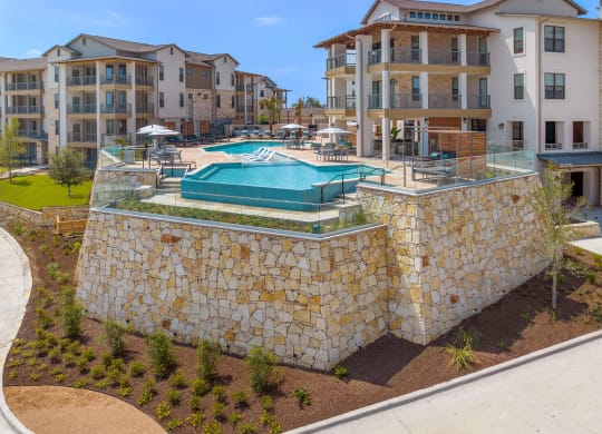an aerial view of a pool with an apartment building in the background