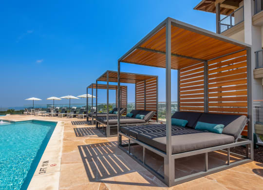 a swimming pool with chaise lounge chairs and a poolside cabana with a