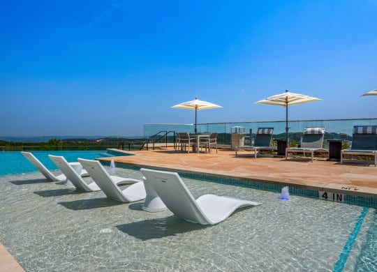 a swimming pool with chairs and umbrellas at a hotel