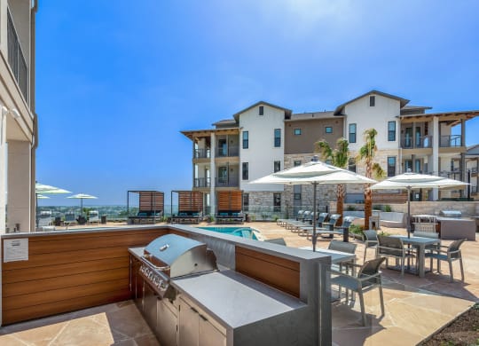 a patio with a hot tub and tables and chairs with umbrellas