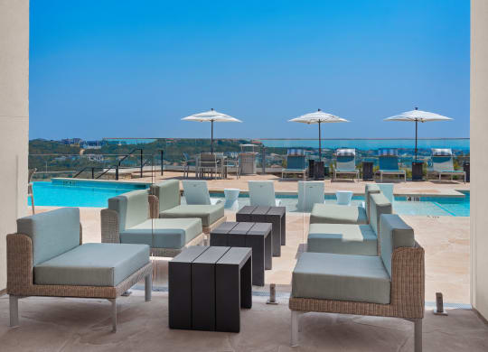 a poolside seating area with blue chairs and umbrellas at a resort