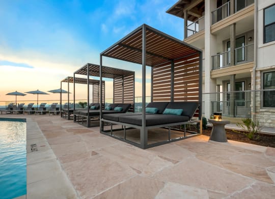 a pool with lounge chairs and umbrellas next to a building with a pool