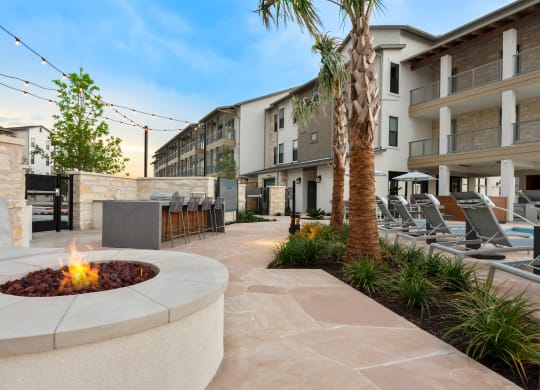 an outdoor patio with a fire pit and lounge chairs