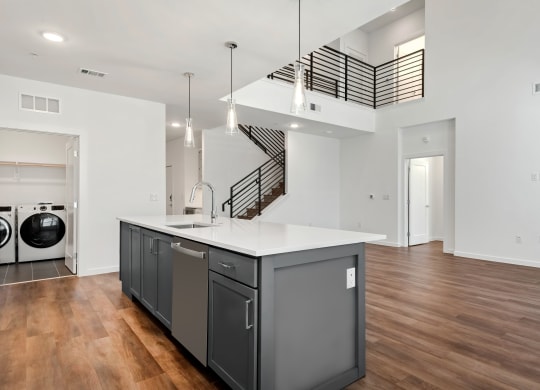 a kitchen with an island and a laundry room with a staircase