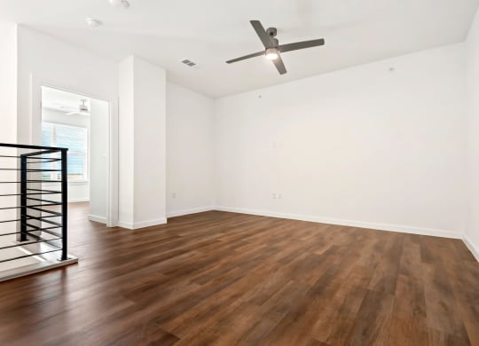 an empty living room with hardwood floors and a ceiling fan
