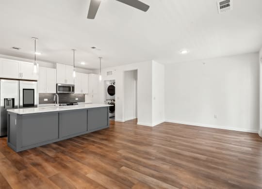 an open kitchen and living room with a wood floor and white walls