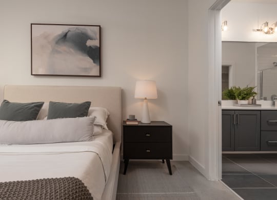 a bedroom with a bed and a night stand and a bathroom