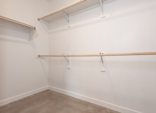 an empty room with white walls and a white walled closet and a wooden rail