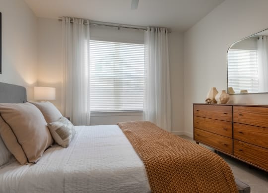 a bedroom with a bed and a dresser and a window