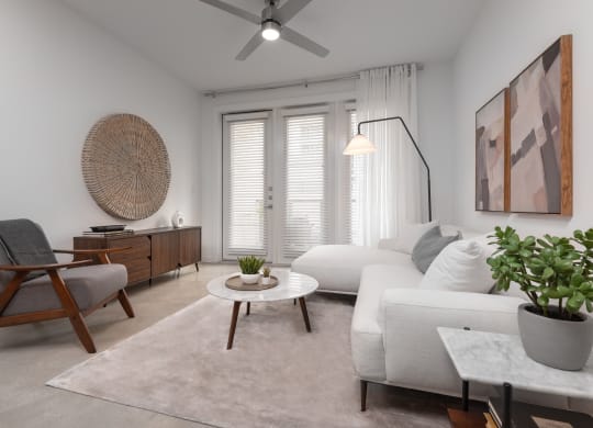a living room with white furniture and a ceiling fan