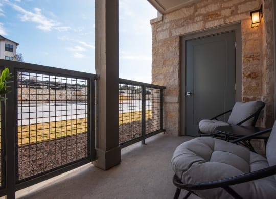 a covered porch with chairs and a door overlooking a body of water