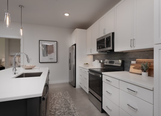 an open kitchen with white cabinets and black appliances and a sink