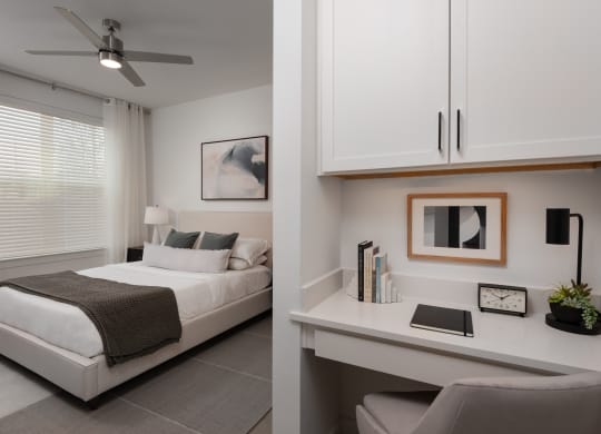 a bedroom with a white bed and a desk and a window