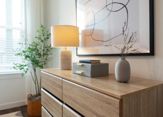 a wooden dresser with a lamp and a vase on it