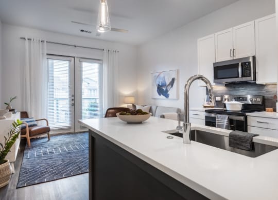 an open kitchen and living room with a sink and a microwave
