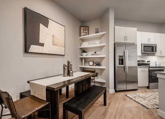 A kitchen with a table and chairs and a painting on the wall.