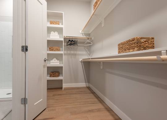 A walk-in closet with white shelves and baskets.
