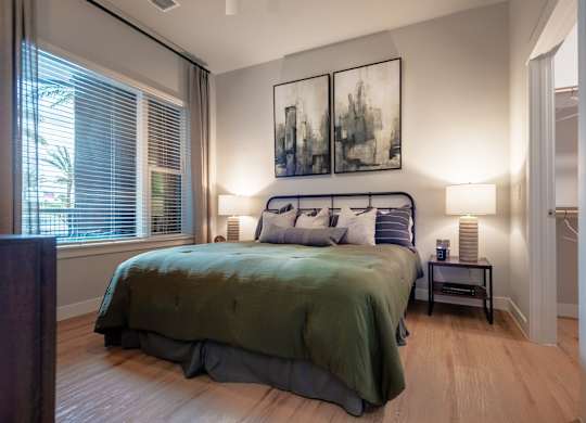 A bedroom with a bed, nightstand, and two framed pictures on the wall.