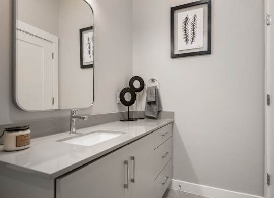 A bathroom with a sink, mirror, and a framed picture on the wall.
