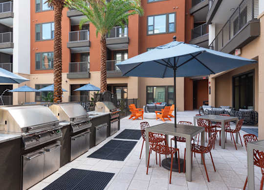 A patio with tables and chairs and umbrellas.