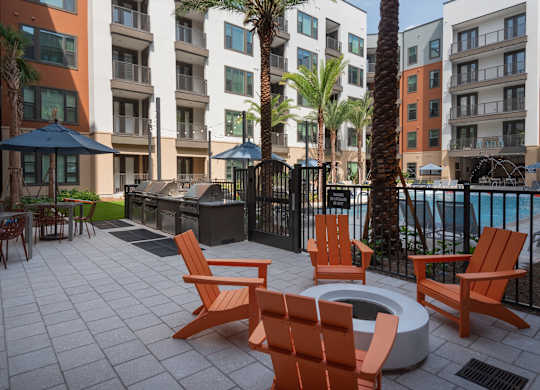 A patio with orange chairs and a fire pit.