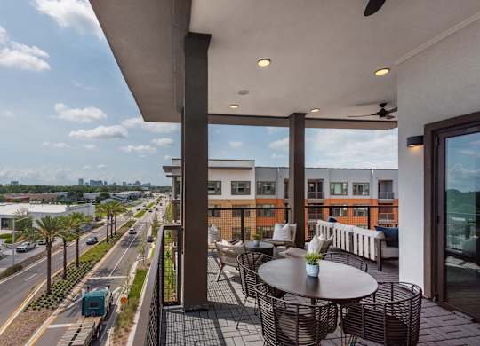 A balcony with a table and chairs overlooks a busy street.