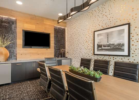 A conference room with a wooden table, chairs, and a television on the wall.