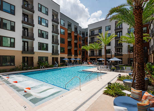 A swimming pool in front of a multi-story apartment building.