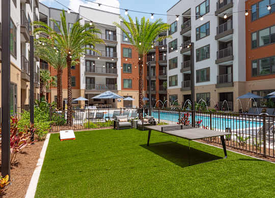 A grassy area with a pool and apartment buildings in the background.