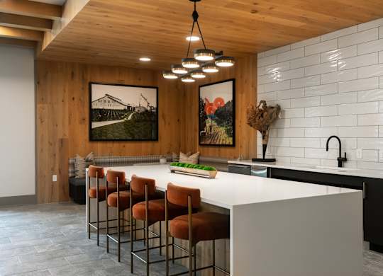A kitchen with a white counter and brown chairs.