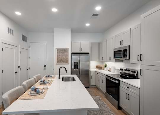 A modern kitchen with a long white table and chairs.