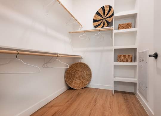 A white closet with a basket and a round straw hat on the floor.